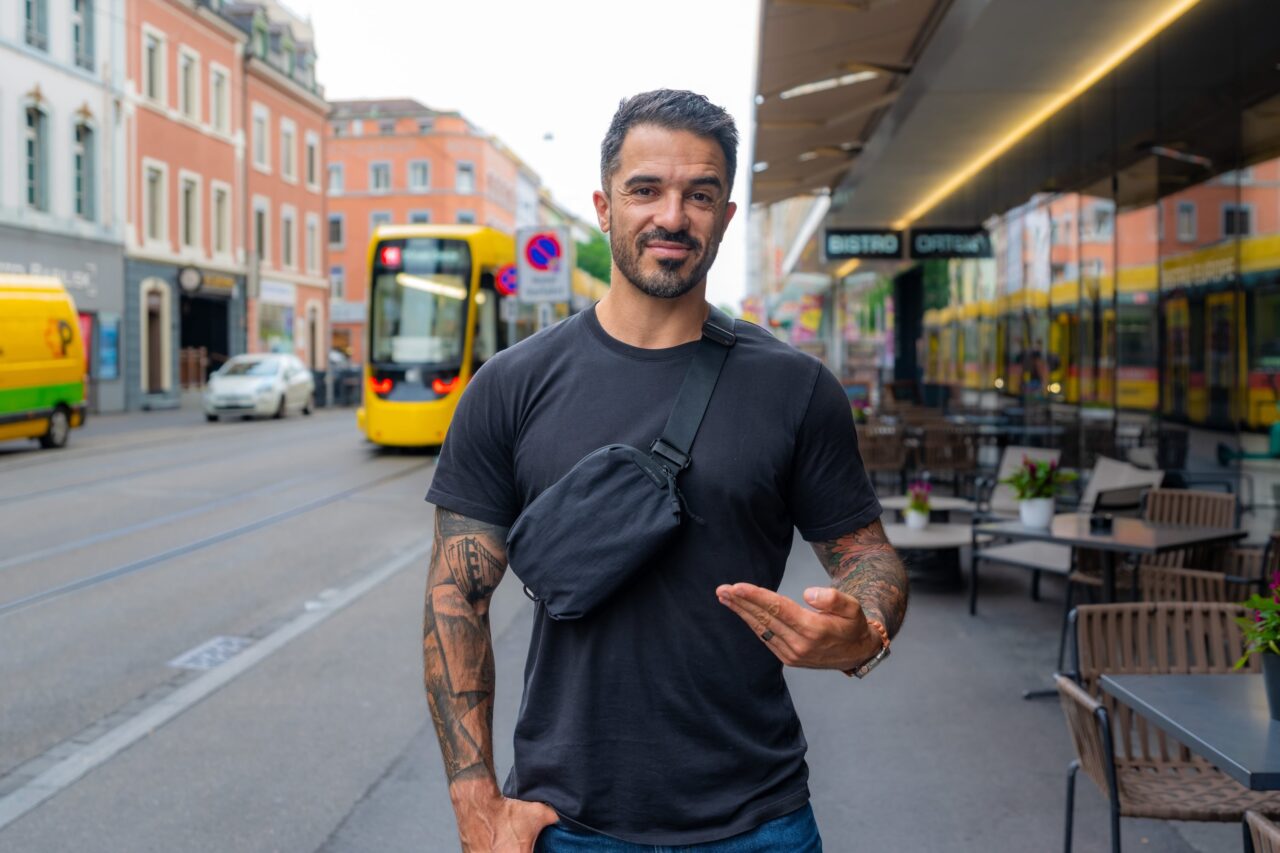 peak design city sling portee LoKan porte la Peak Design City Sling 2L noire en bandoulière dans une rue de Bâle