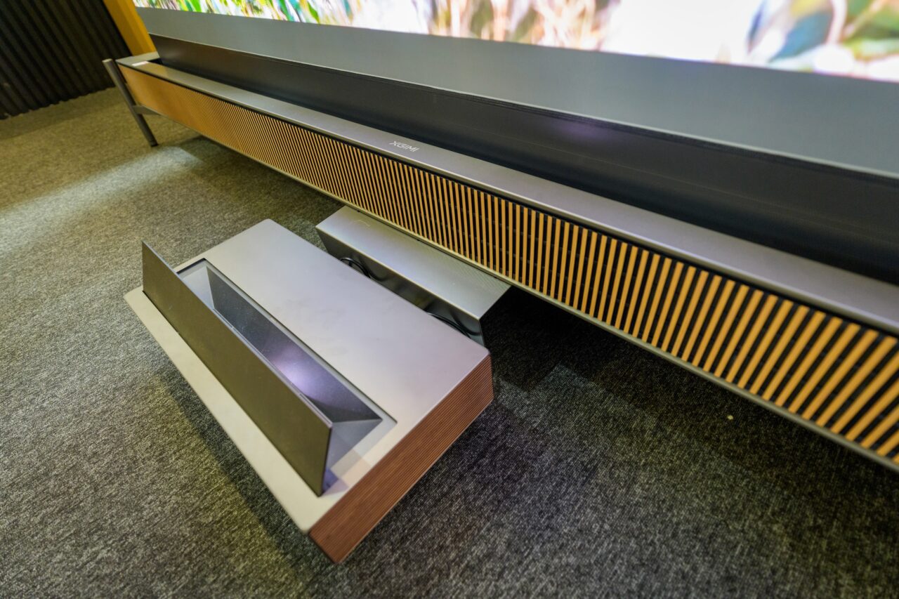 Projecteur XGIMI Aura 3 Max placé devant le meuble intégrant la barre de son et la toile