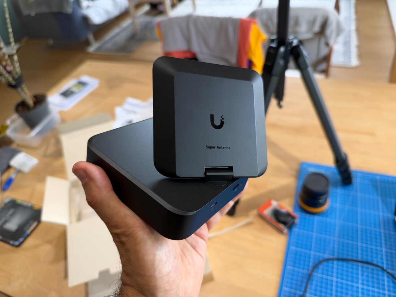 UniFi AirWire noir tenu en main, avec son antenne directionnelle Super Antenna relevée.